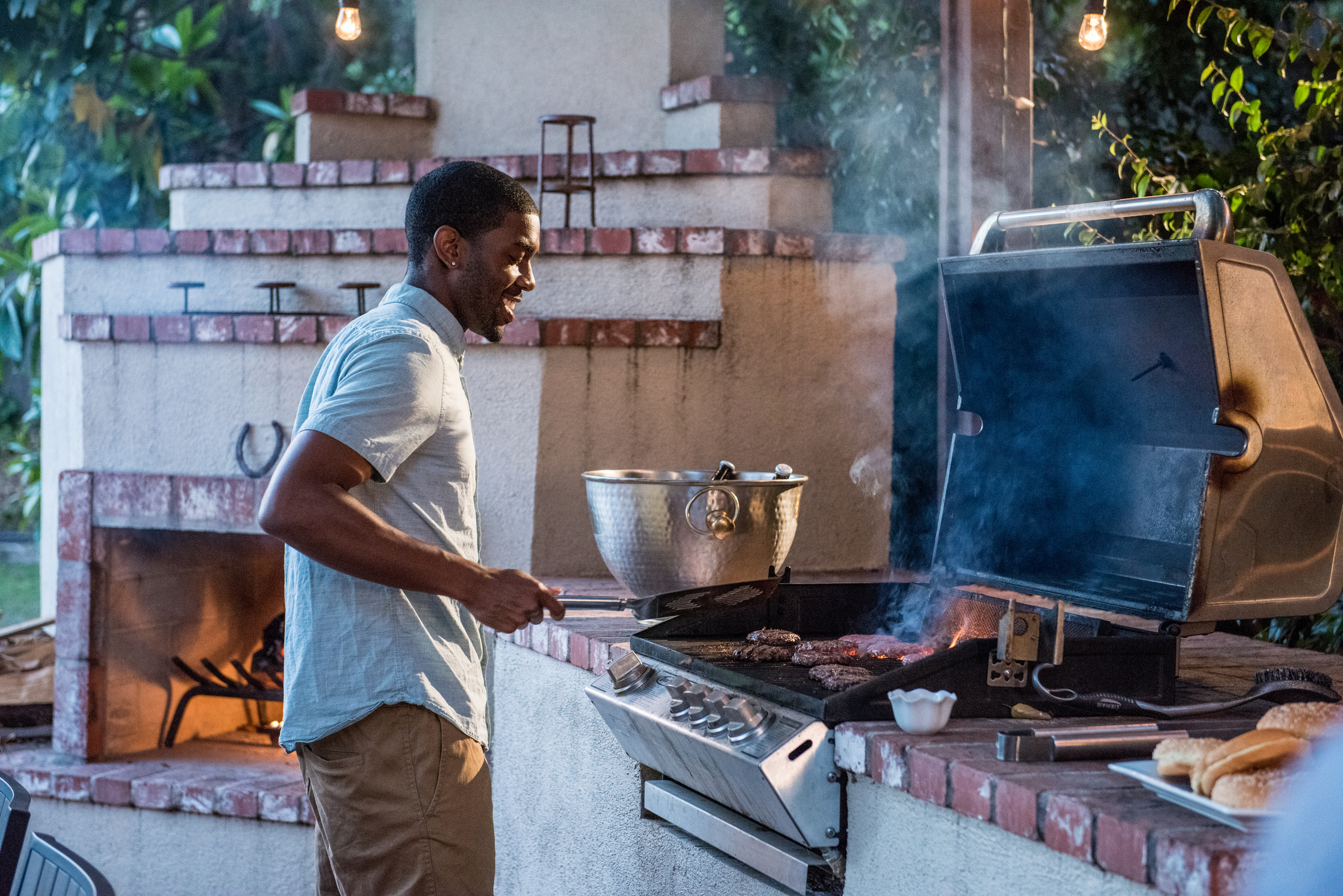 A man smiling while preparing food on a grill A man smiling while preparing food on a grill